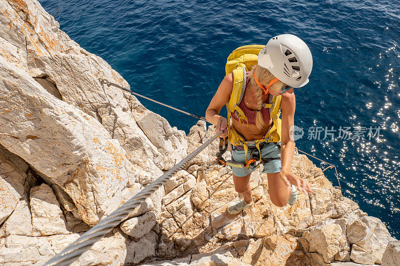 费拉塔岛(Via Ferrata)上的攀登者，年轻的妇女们在攀登海面上的岩石